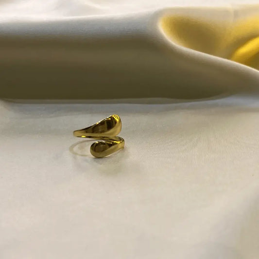 Bague Iris en acier inoxydable dorée avec un design unique, posée sur un fond en tissu