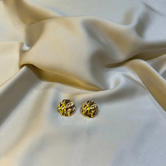 Boucles d'oreilles rondes en acier inoxydable avec une texture martelée, posées sur un fond en tissu