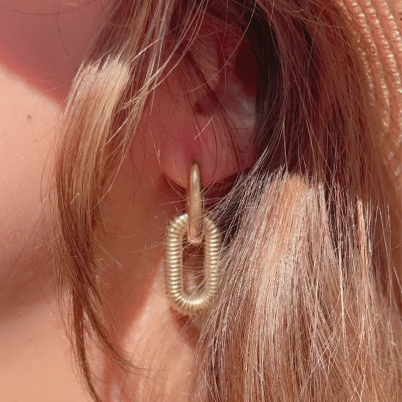 Boucle d’oreille en acier inoxydable doré avec design de chaînes, portée pour un look moderne.