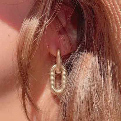 Boucle d’oreille en acier inoxydable doré avec design de chaînes, portée pour un look moderne.