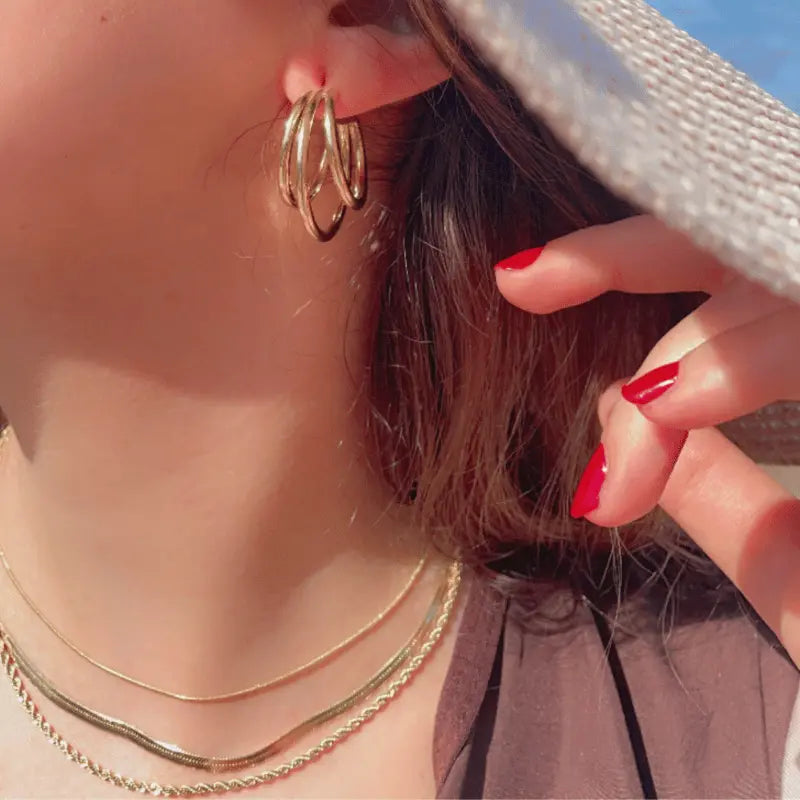 Boucles d'oreilles créoles en acier inoxydable dorées portées avec un collier assorti