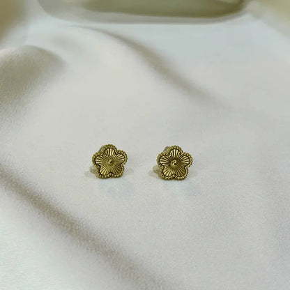 Boucles d'oreilles en acier inoxydable dorées en forme de fleur, posées sur un fond en tissu sous un autre angle