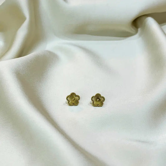 Boucles d'oreilles en acier inoxydable dorées en forme de fleur, posées sur un fond en tissu