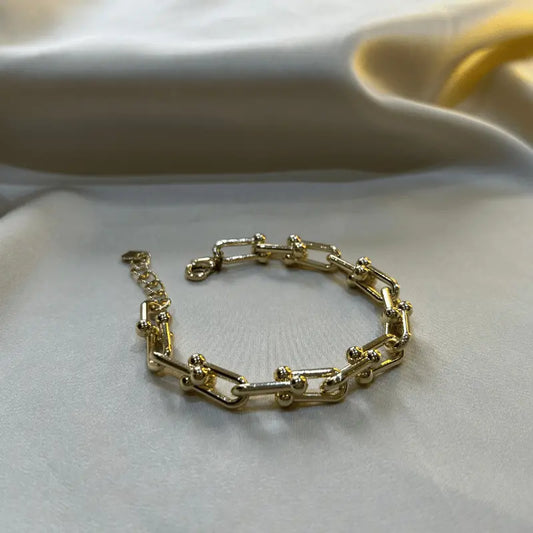 Bracelet Lucia en acier inoxydable doré à maillons, posé sur un fond en tissu