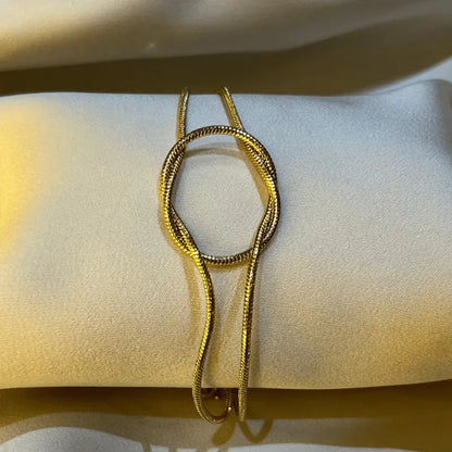 Gros plan sur un bracelet doré en acier inoxydable, posé sur un fond en tissu.
