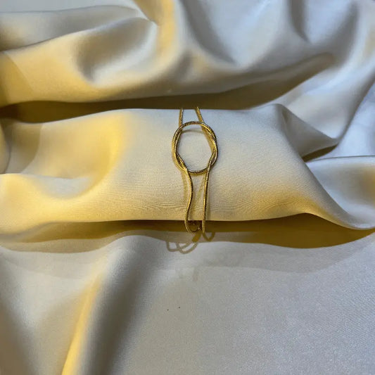 Bracelet en acier inoxydable doré, disposé élégamment sur un fond en tissu.
