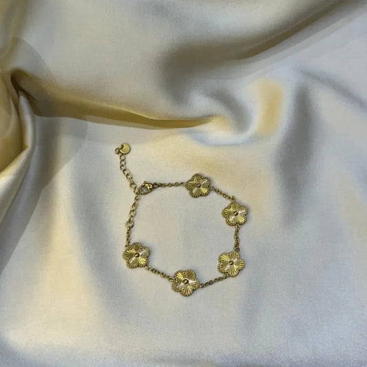 Bracelet en acier inoxydable doré avec motifs floraux, posé sur un fond en tissu