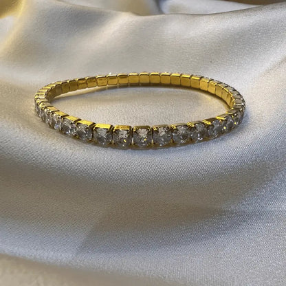 Bracelet en acier inoxydable doré avec des pierres étincelantes, en gros plan sur fond en tissu