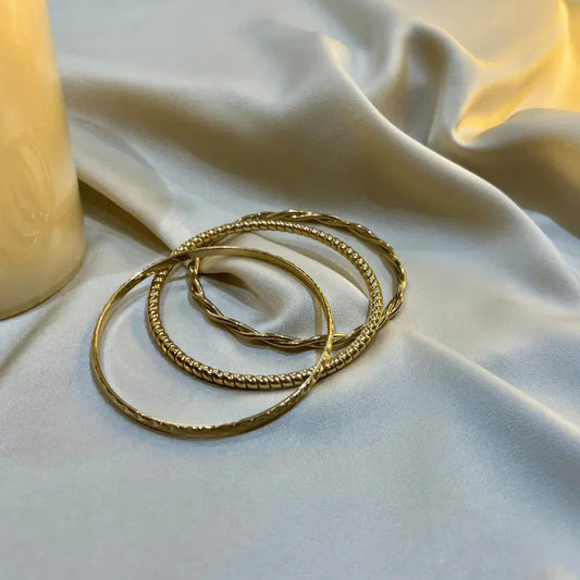 Ensembles de trois bracelets en acier inoxydable élégants disposés sur un tissu