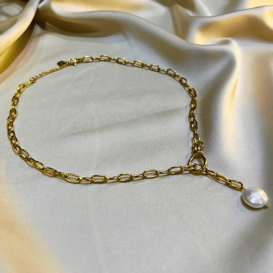 Collier en acier inoxydable doré avec une chaîne et une perle, posé sur un fond en tissu