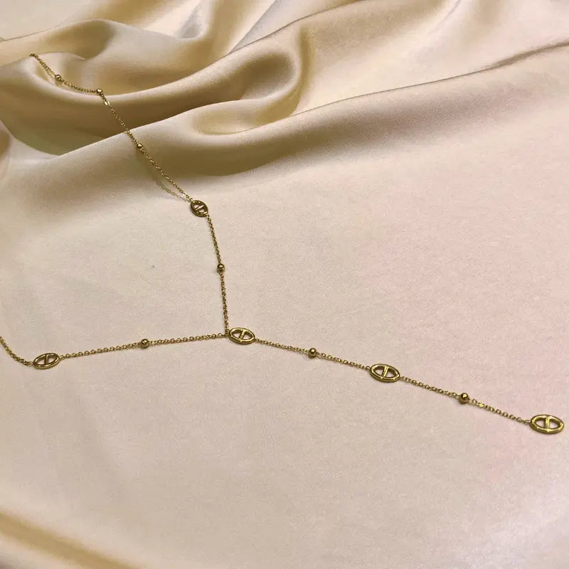 Collier long en acier inoxydable en forme de Y sur fond beige élégant